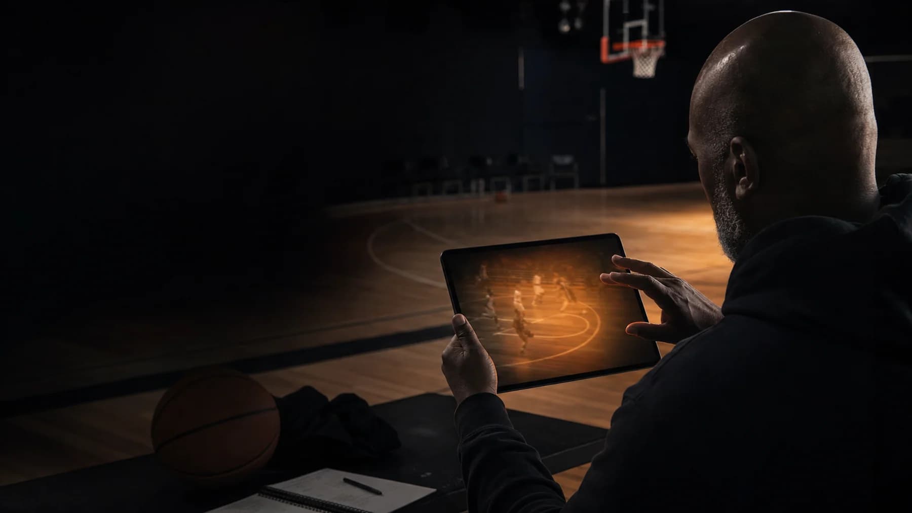 A basketball coach pauses to inspect an uncertain video moment before acting